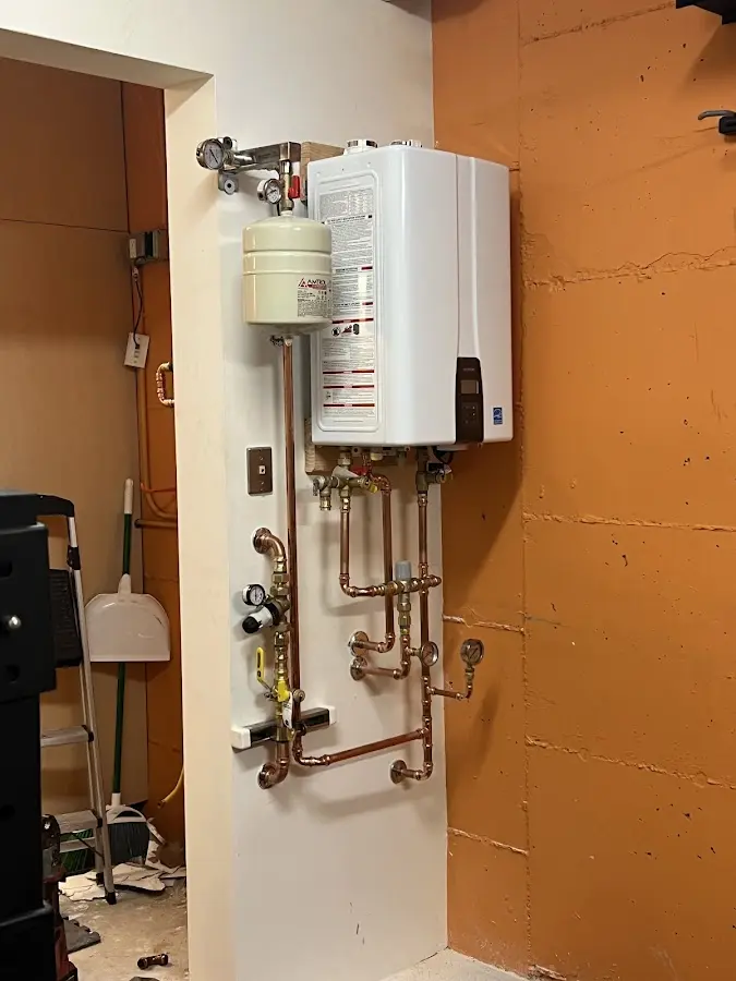 Plumbing technician inspecting water heater connections in Winfield